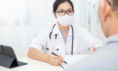 Doctor wearing mask speaks to patient